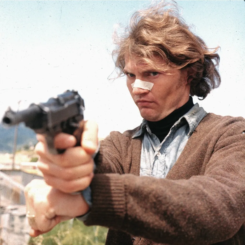 a man holding a gun in his right hand as he walks toward the camera