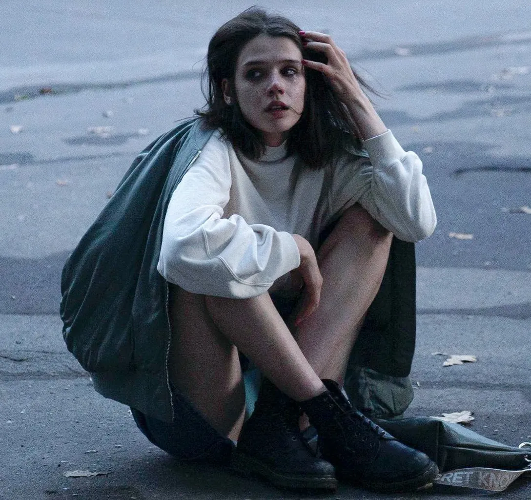 a woman sitting on the ground with her hand on her head