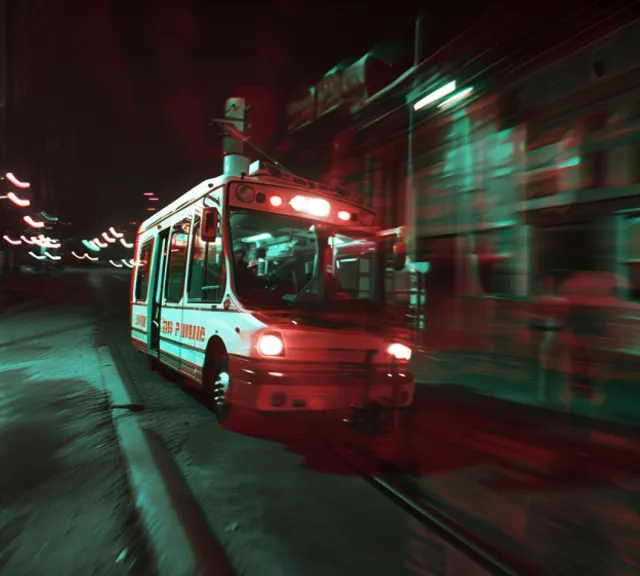 a red and white bus driving down a street at night