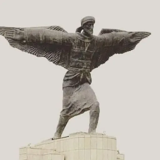 Winged man statue surrounded by greenery and natural elements on a rooftop overlooking the city