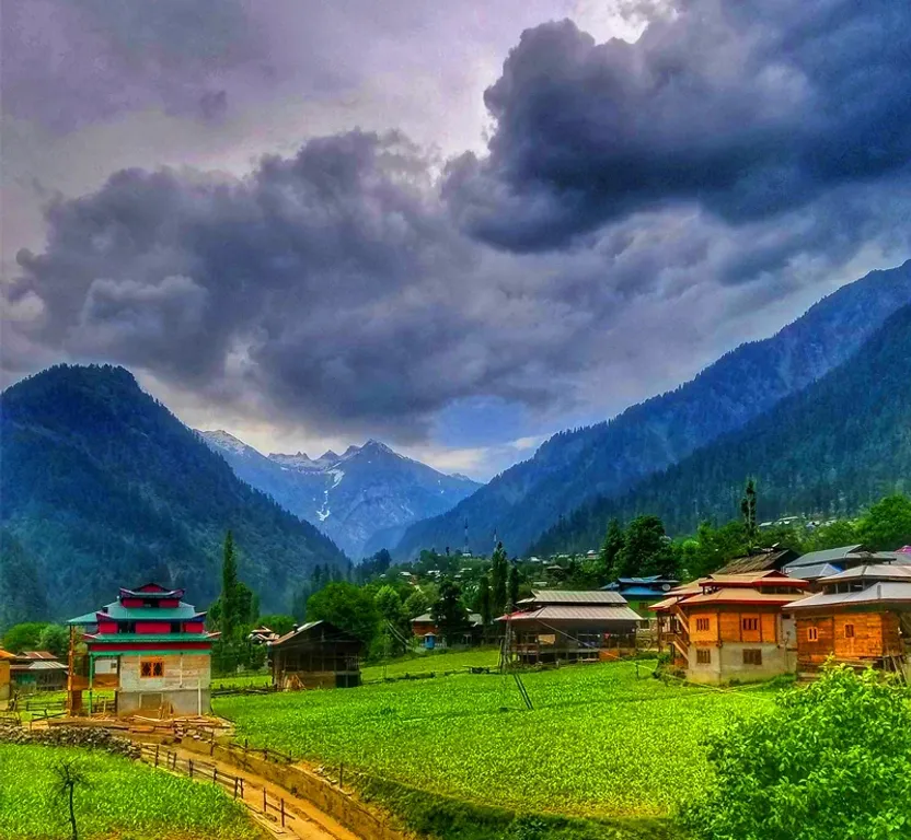 a scenic view of a village with mountains in the background