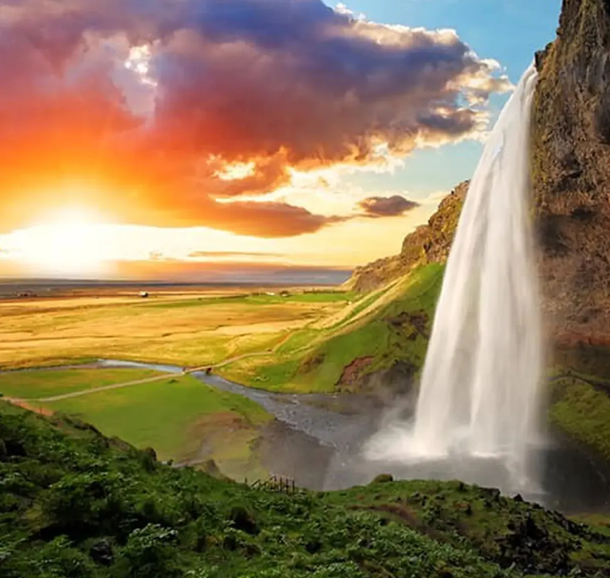 a waterfall with a sunset in the background