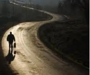 a man walking down a dirt road next to a forest