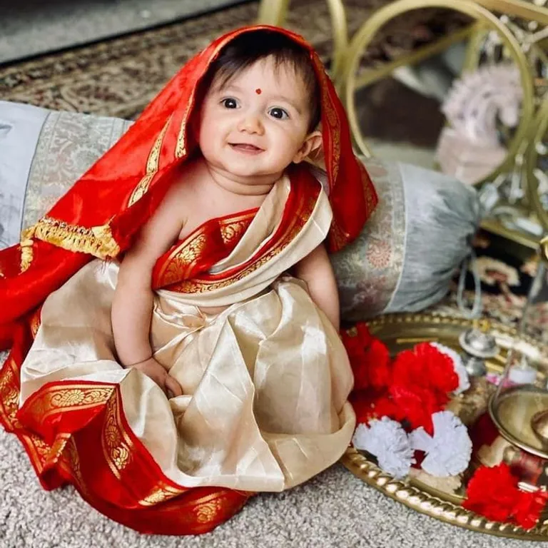 a baby dressed in a sari sitting on the ground