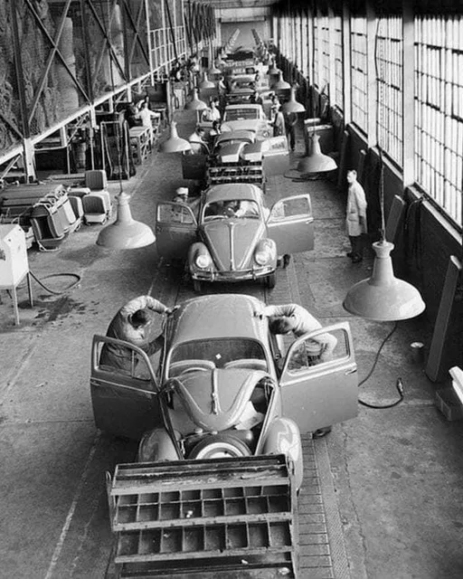 a black and white photo of a car assembly line