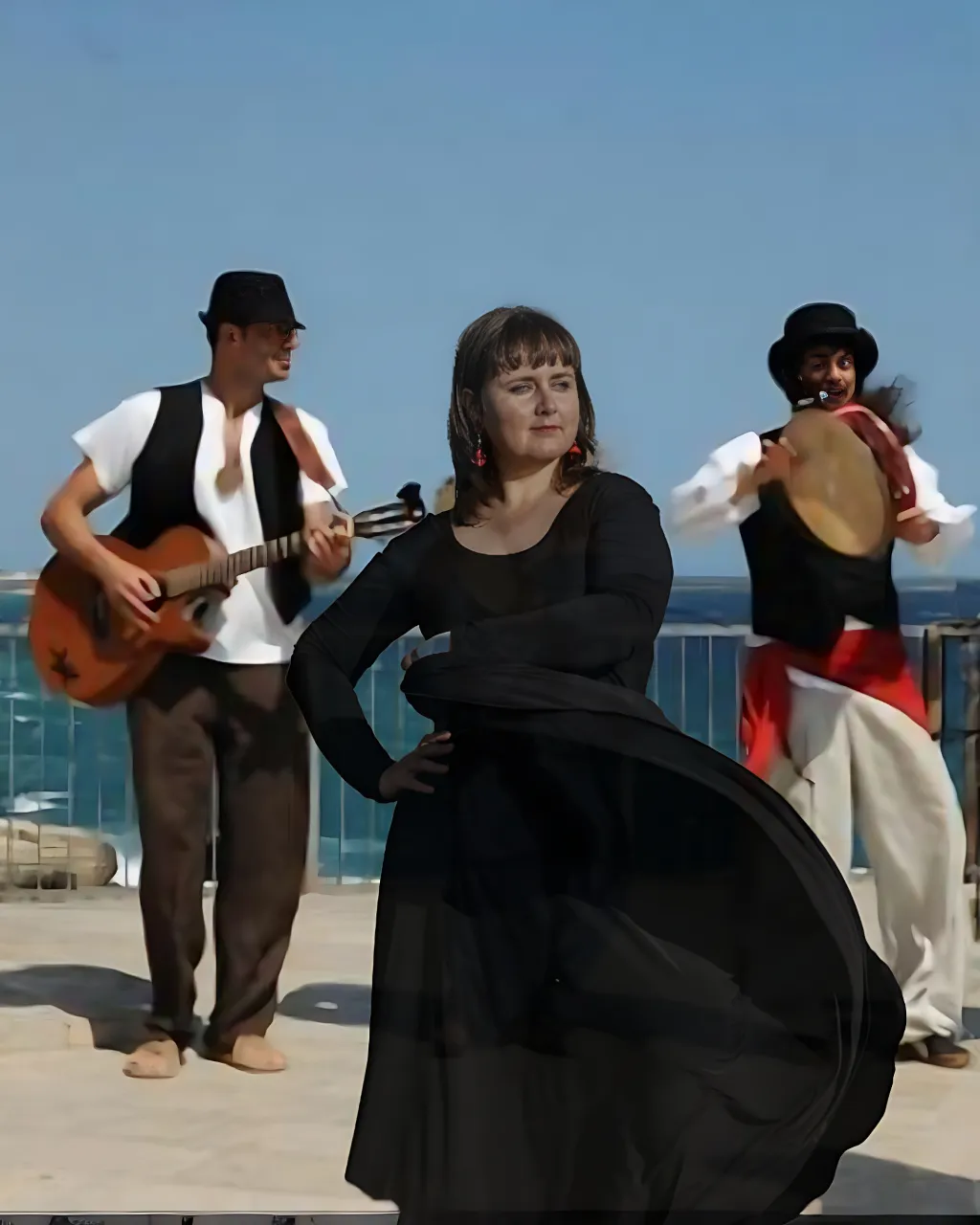 a woman in a long black dress standing next to a man with a guitar