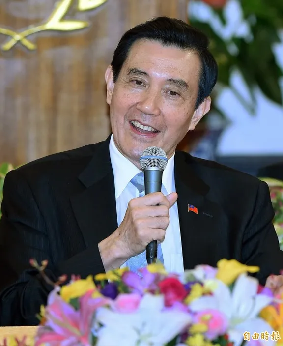 a man in a suit holding a microphone laughing