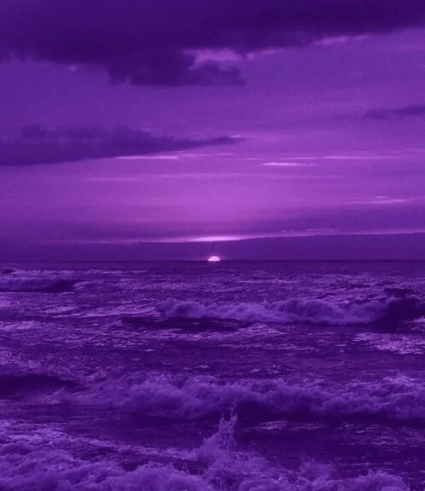 a purple sky over the ocean with waves