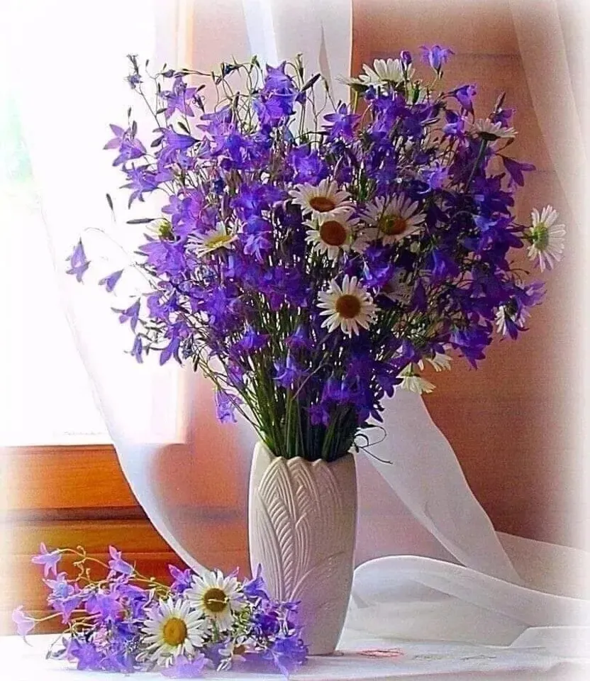 a white vase filled with purple and white flowers