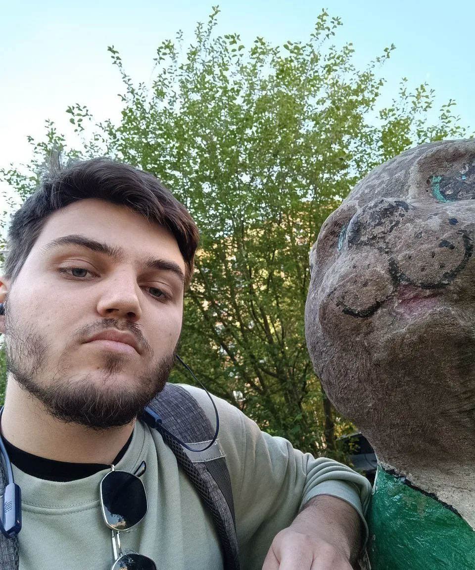 a man standing next to a statue of a cat