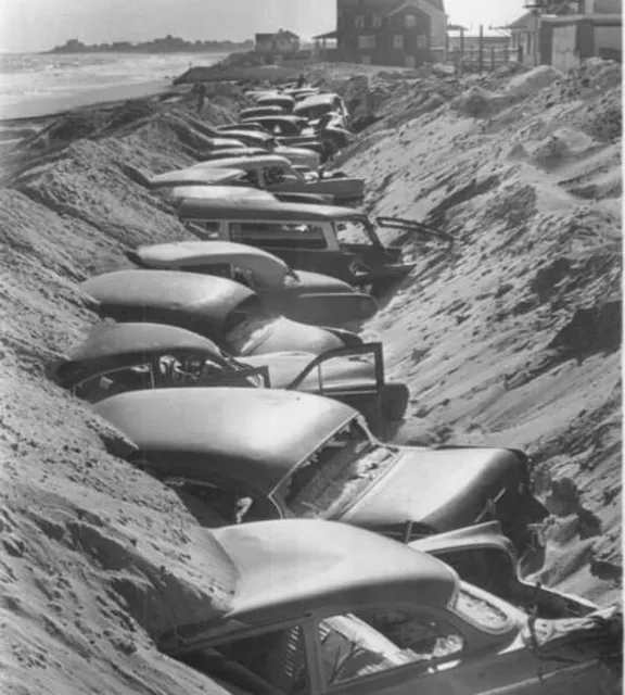 a line of cars parked on top of a sandy beach