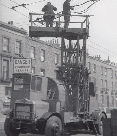 a couple of men standing on top of a utility truck