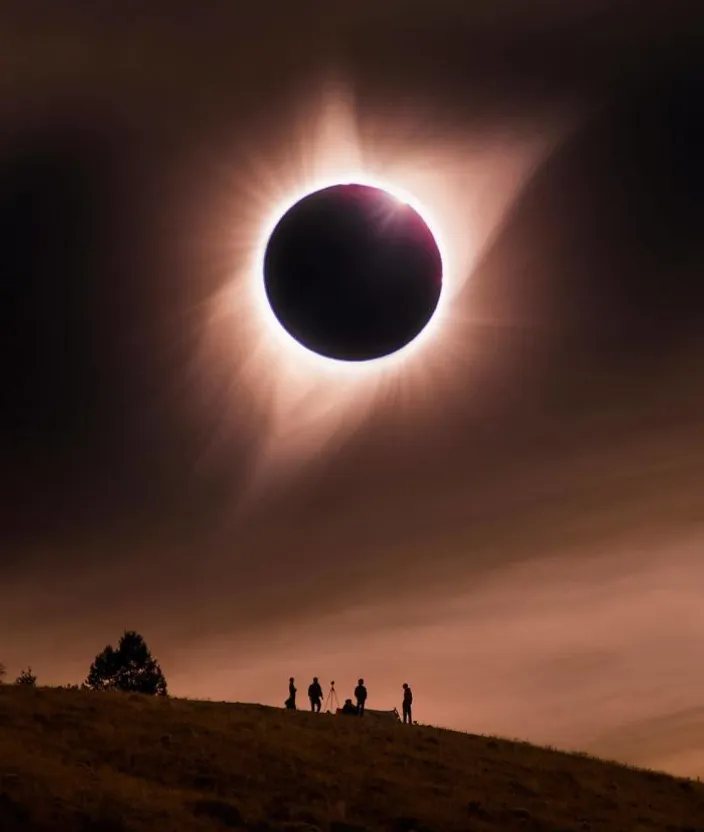 a solar eclipse is seen over a hill