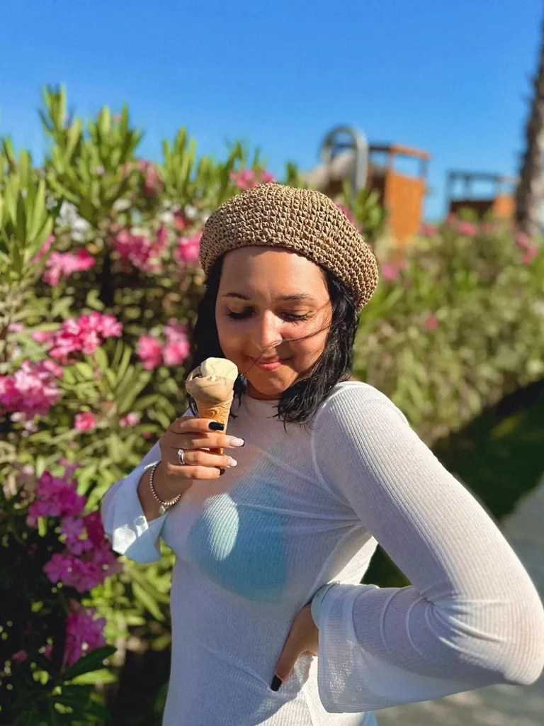 Woman in a black and white setting eating a brightly colored ice cream cone