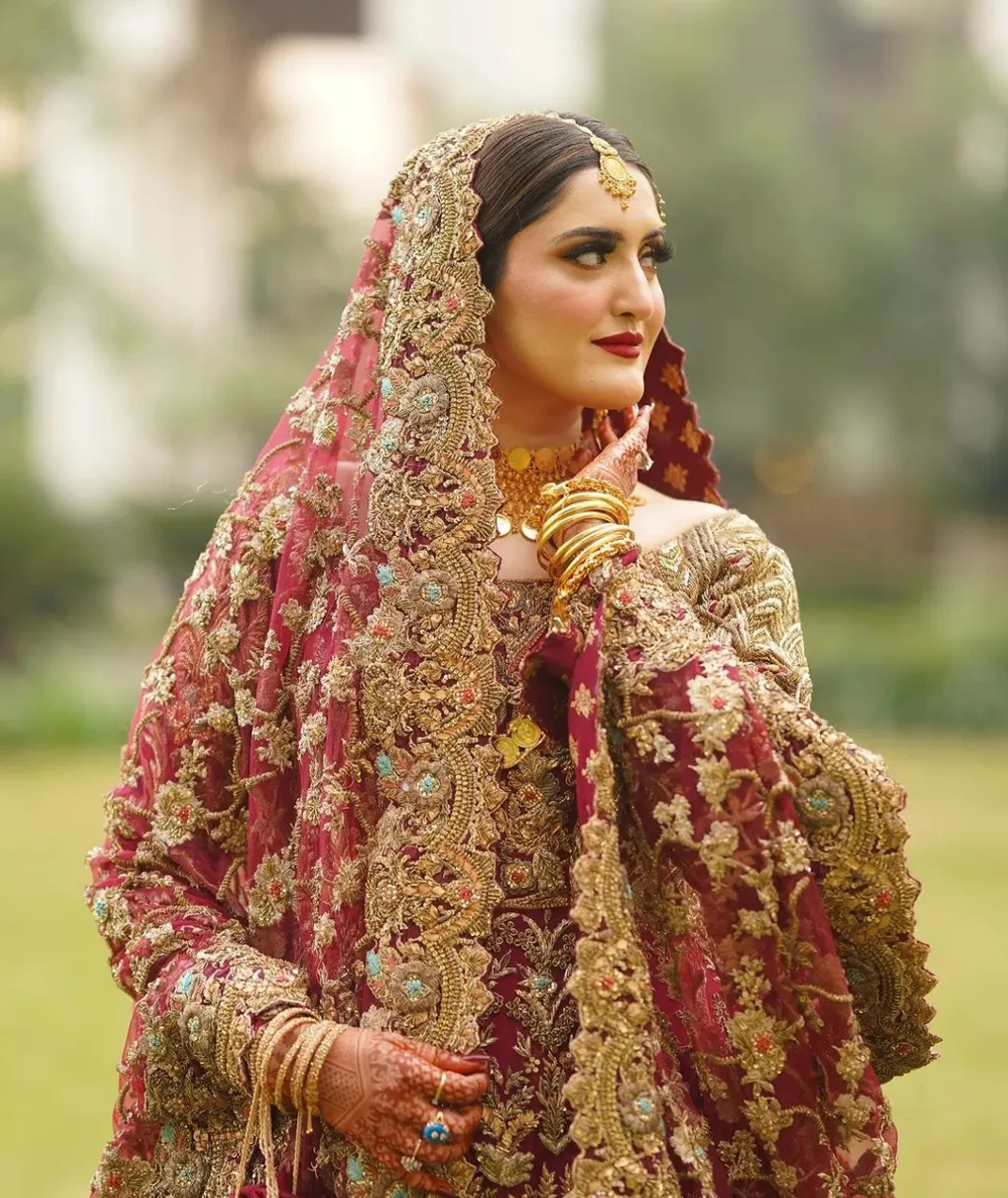 A woman in red and gold bridal dress standing in a peaceful cherry blossom garden