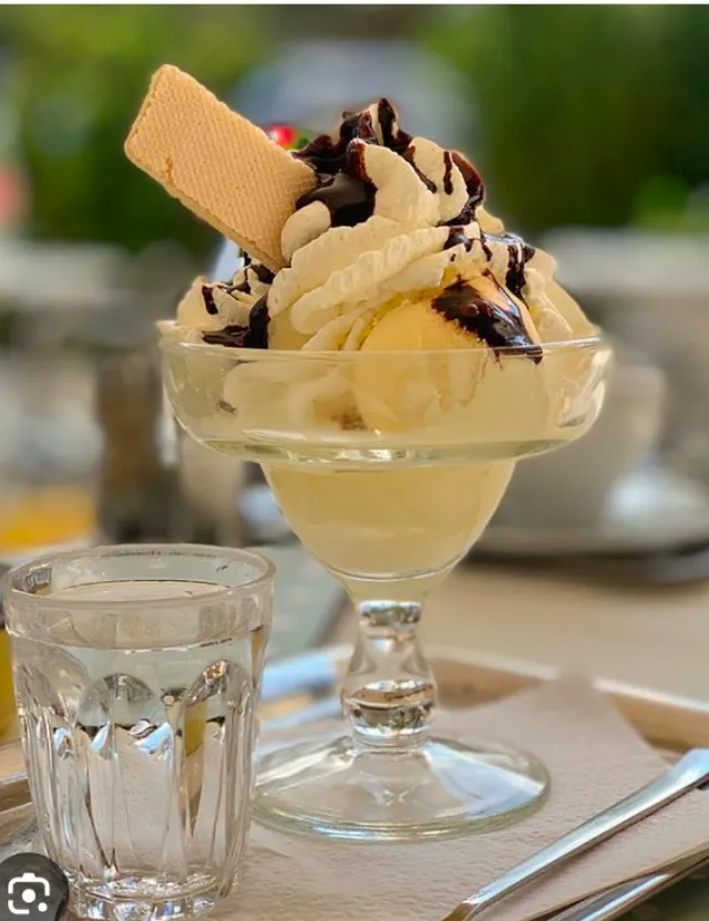 an ice cream sundae with a spoon and a glass of water on a table.