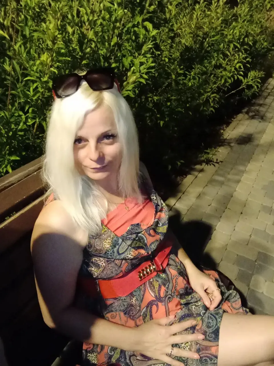 a woman with white hair and sunglasses sitting on a bench