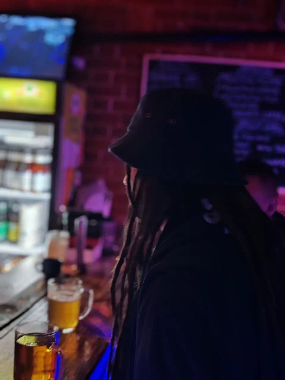A man with dreadlocks sitting in an urban jazz club, the warm light of the stage illuminating his face and hair