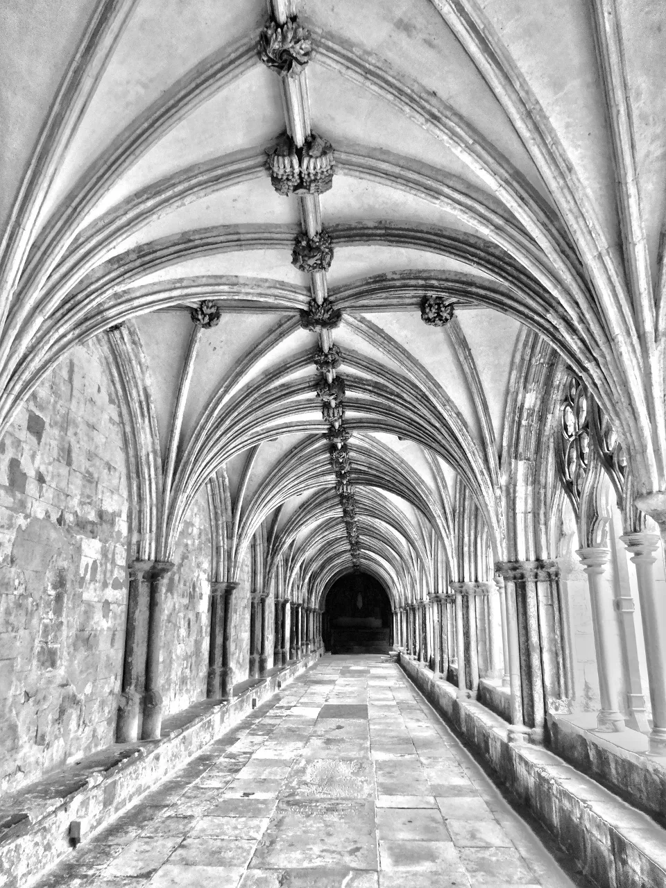 Long hallway of an abandoned asylum with shadowy figures lining the walls, in black and white photo with high contrast