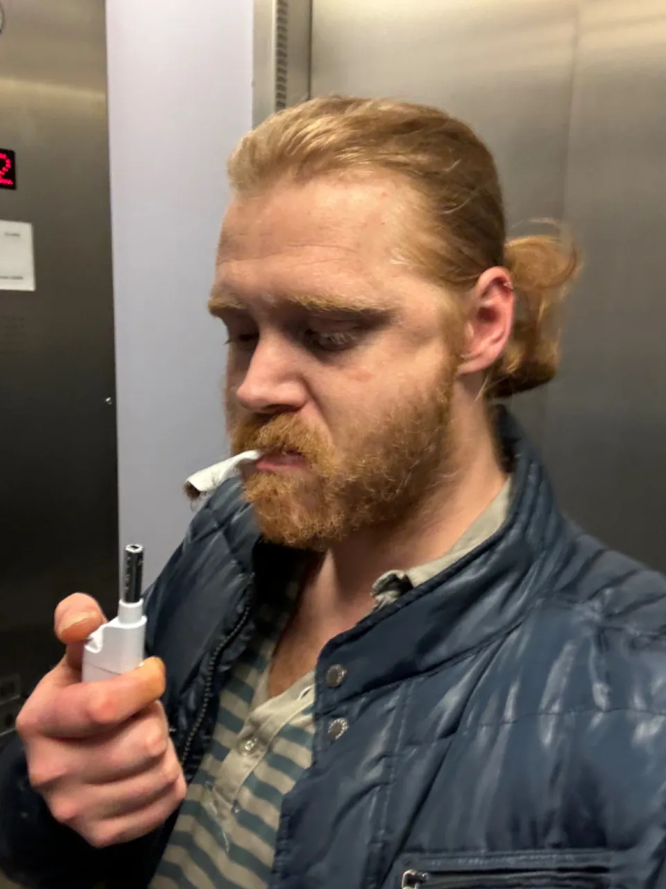 a ginger man with a beard is smoking a cigarette