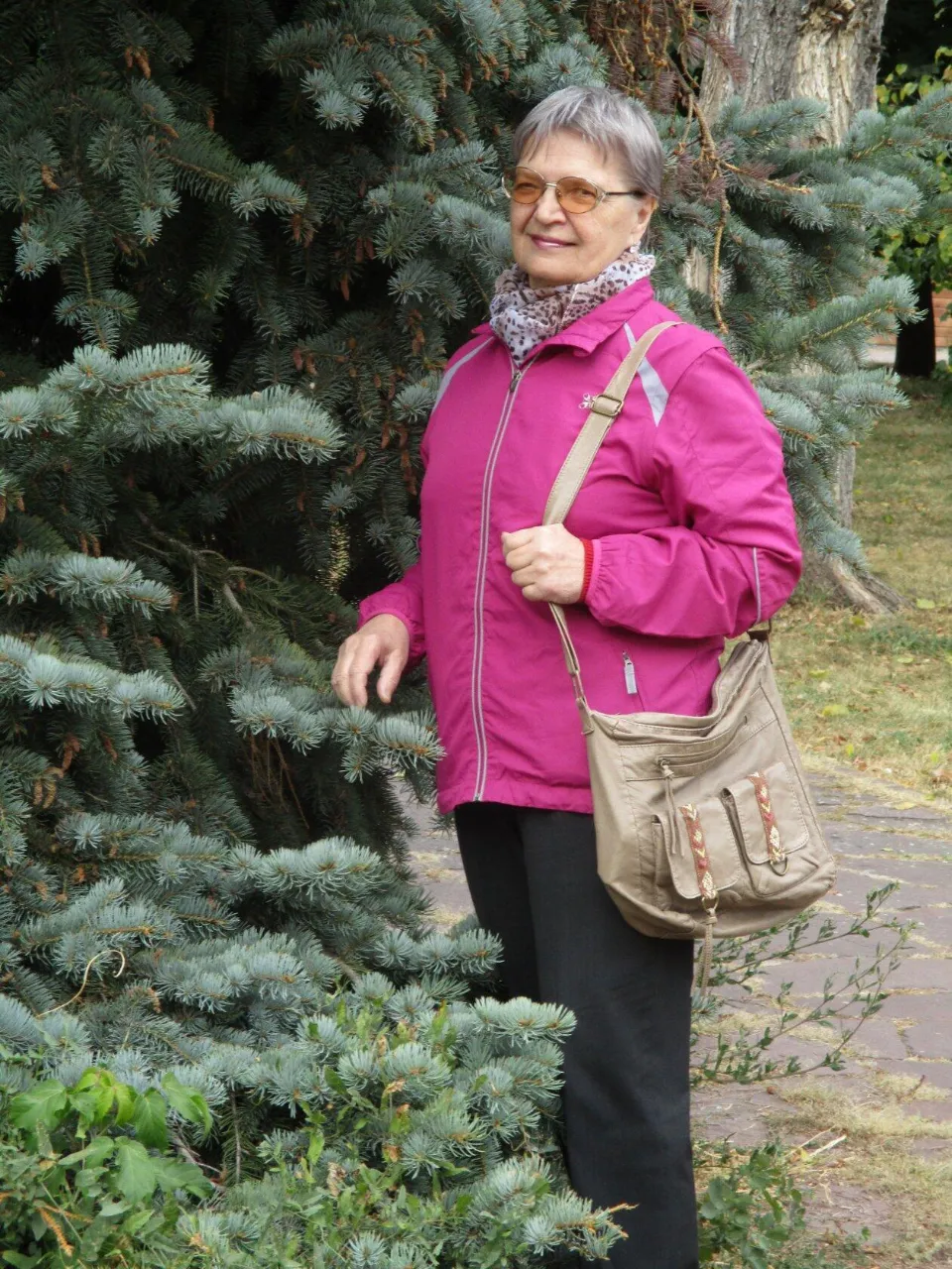 a woman standing next to a tree holding a purse