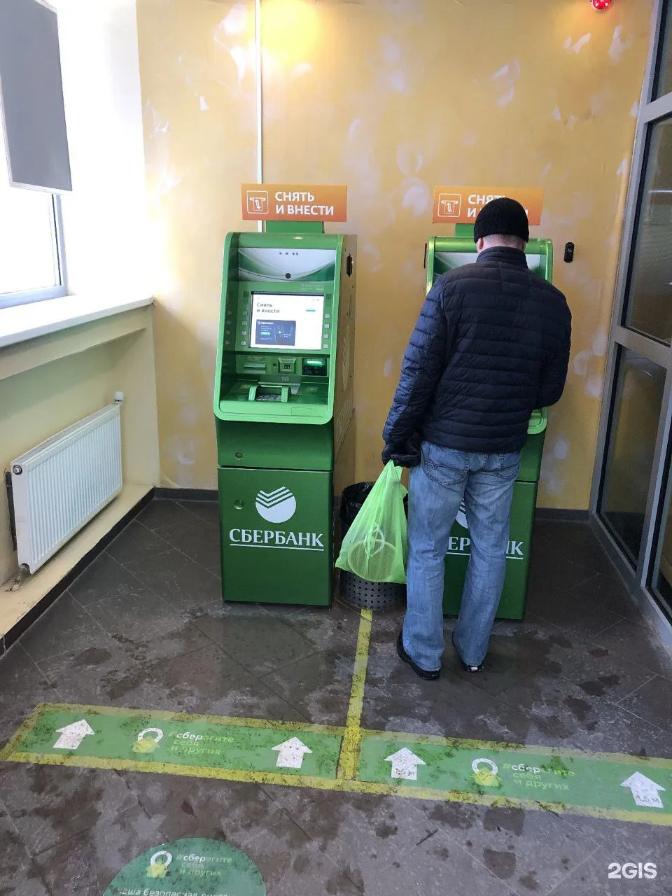 a man standing in front of a green atm machine