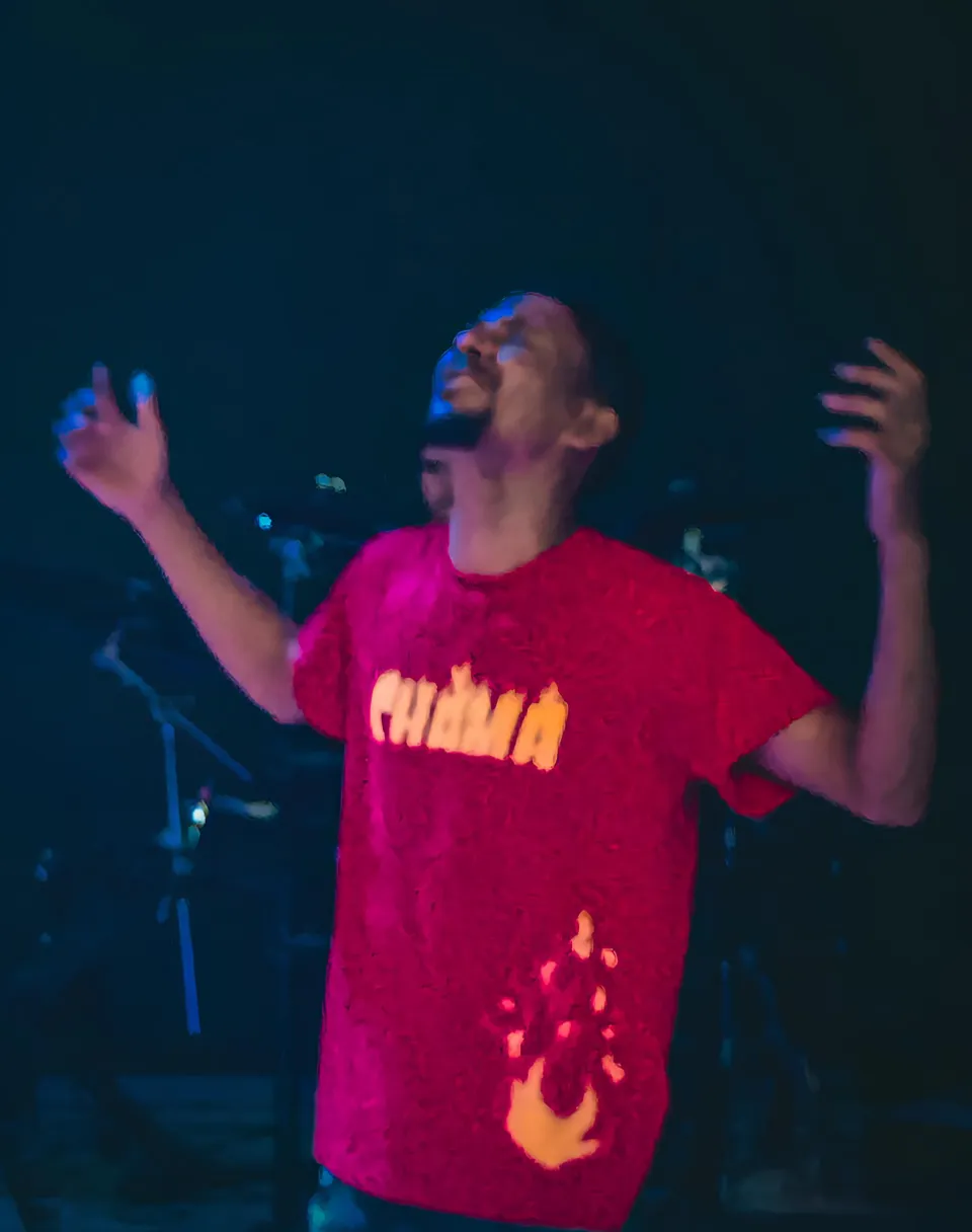 A man in a red shirt praying in church and being illuminated by the Holy Spirit.