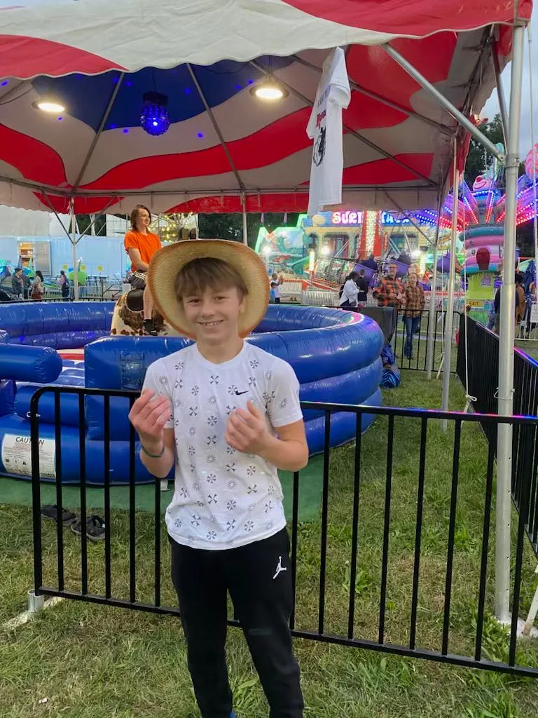 a young boy standing in front of an inflatable pool