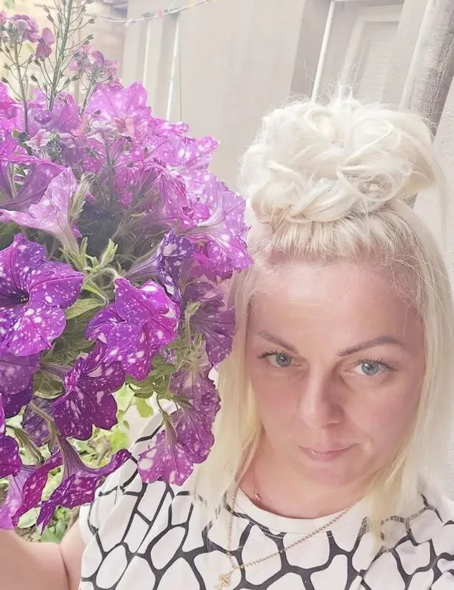 a woman holding a bunch of purple flowers