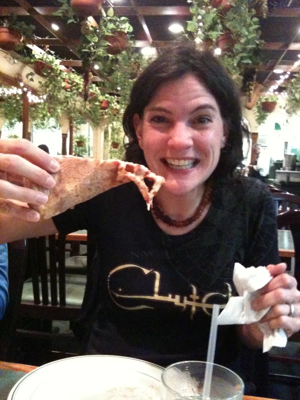 a woman sitting at a table eating a slice of pizza