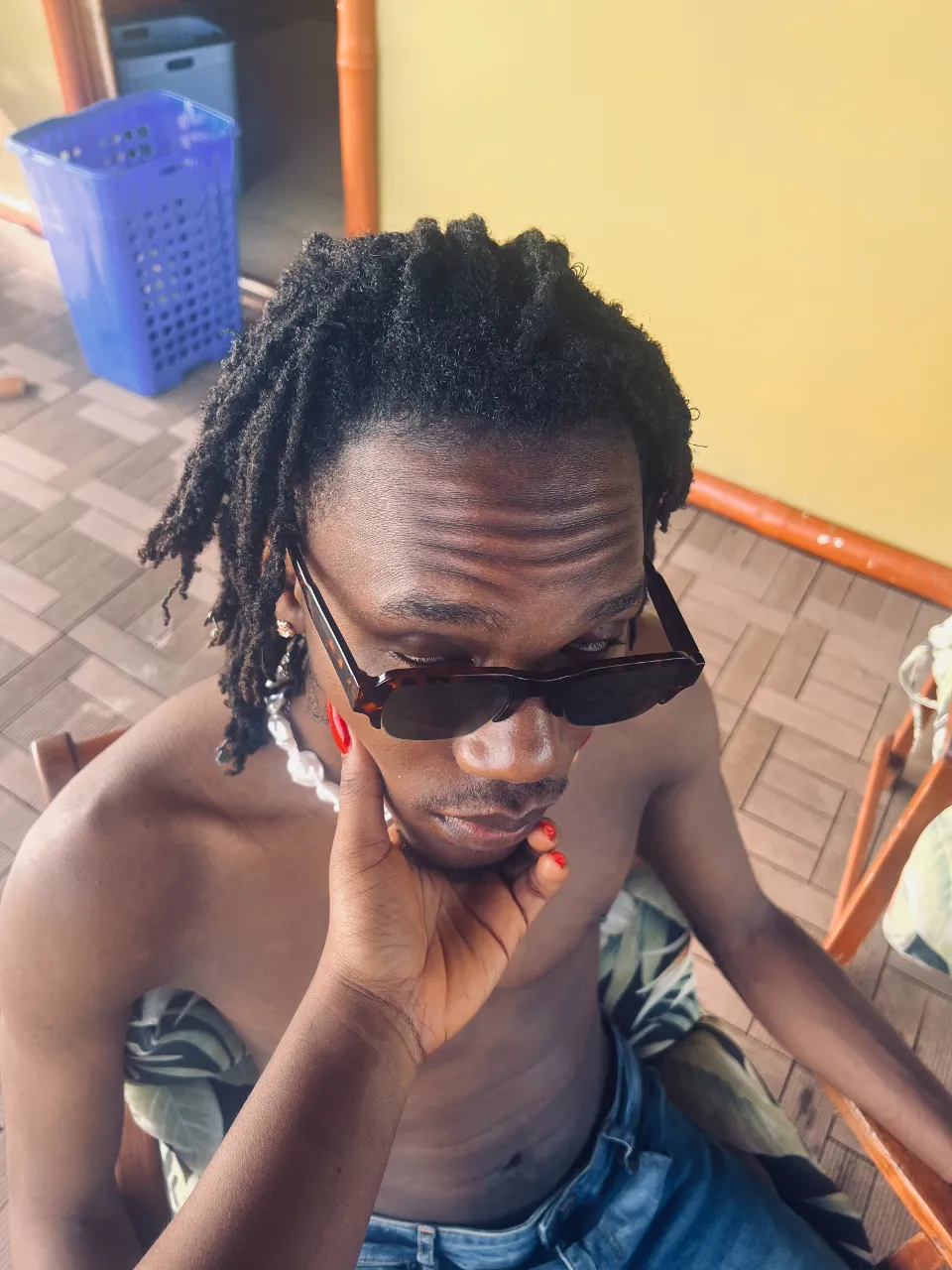 a man with dreadlocks wearing shades, a female hand holds his chin raising his head up slightly