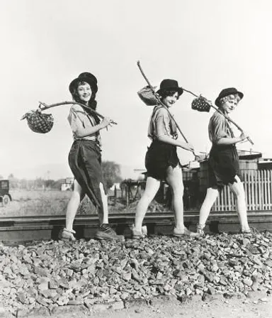 Vagrant women walking In the same direction along a train track with bundles on their shoulders Two feet two hands   