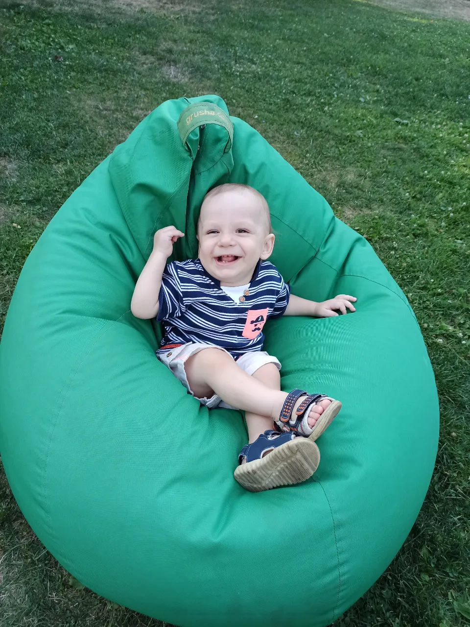 A little boy sitting on a bean bag chair in outer space, holding a toy spaceship and gazing at the stars