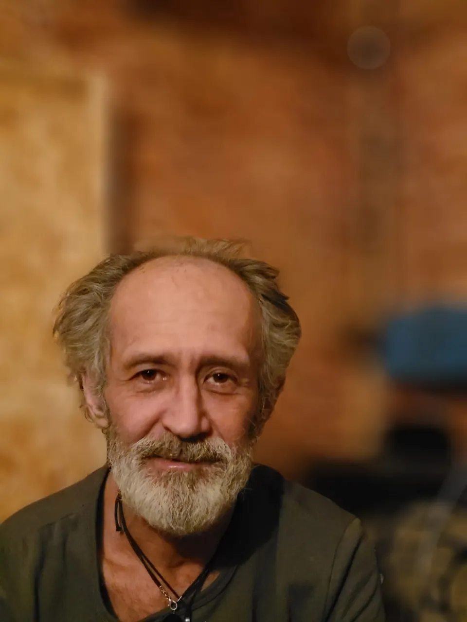 Close up of a person with a beard posed in rustic background with natural textures