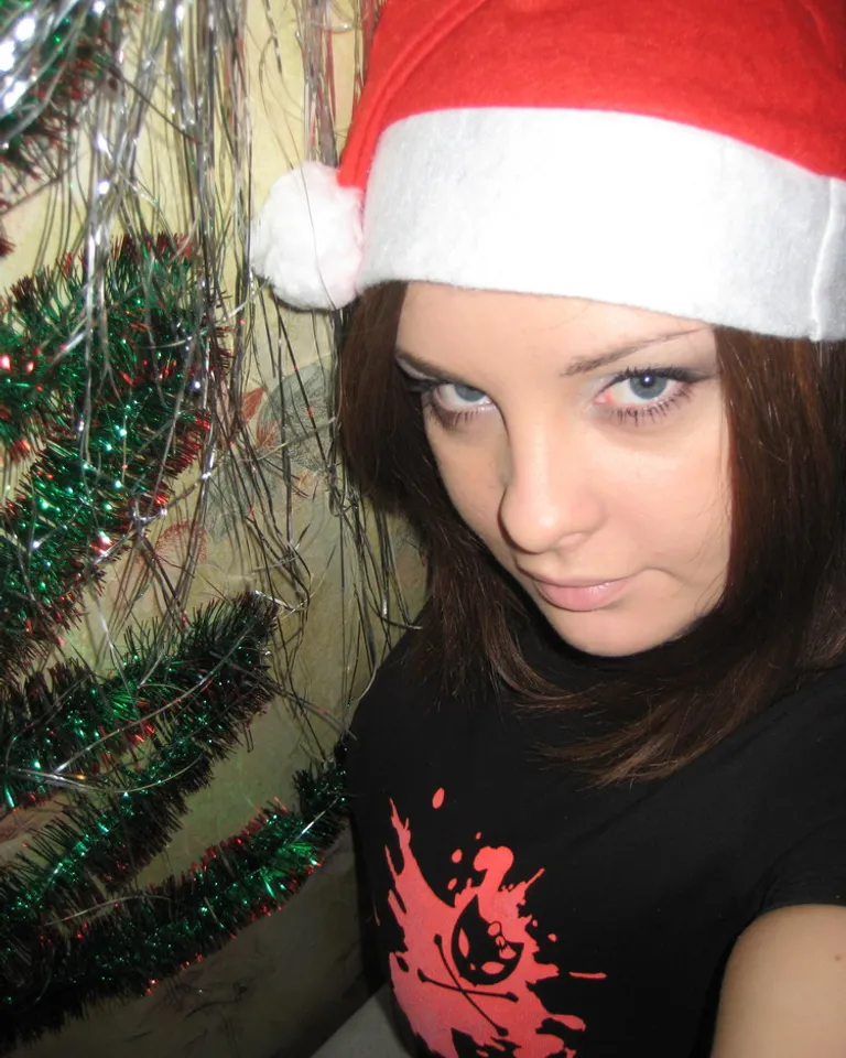 a woman wearing a santa hat next to a christmas tree