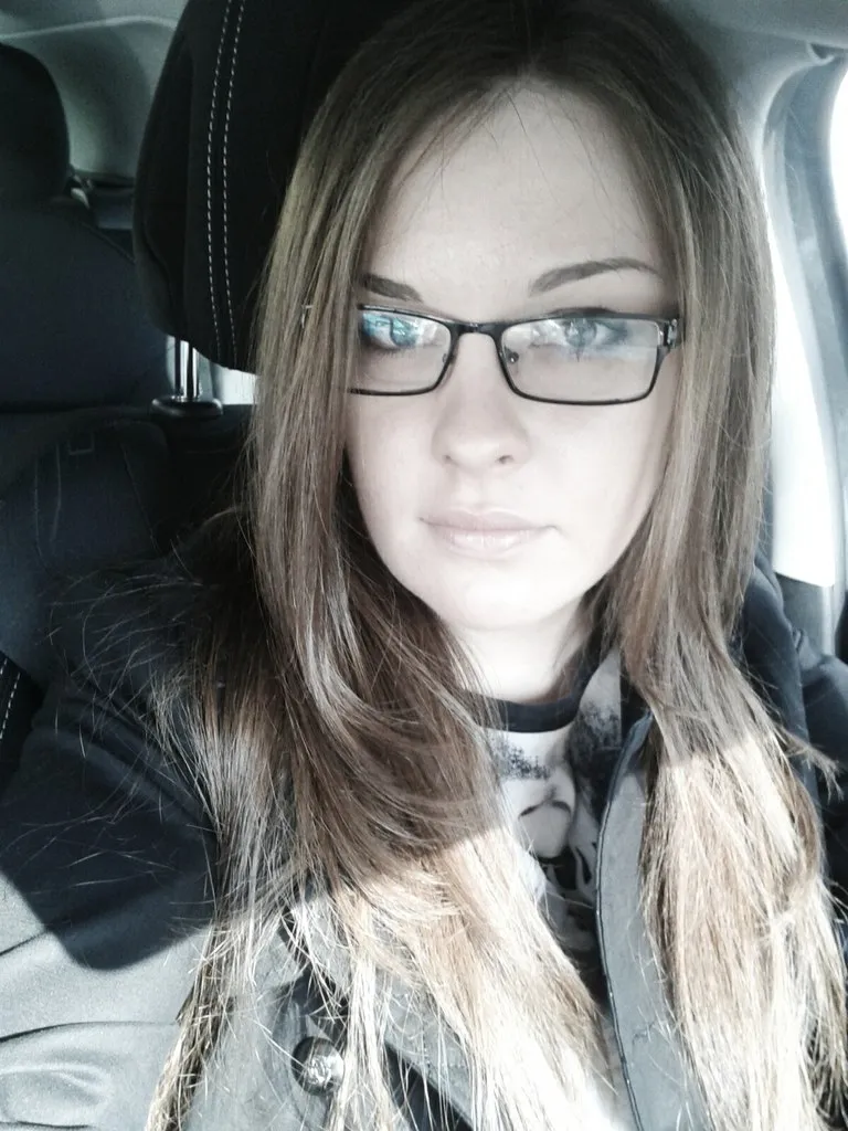 a woman wearing glasses sitting in a car