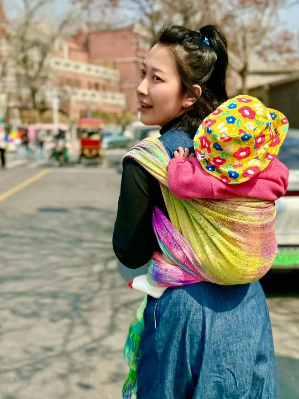 a woman walking down a street carrying a child on her back