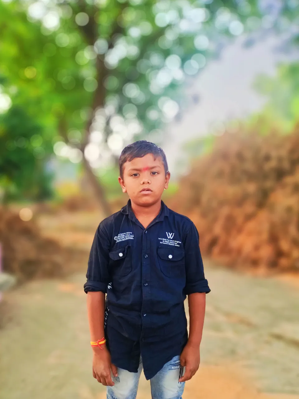 a young boy standing in the middle of a dirt road