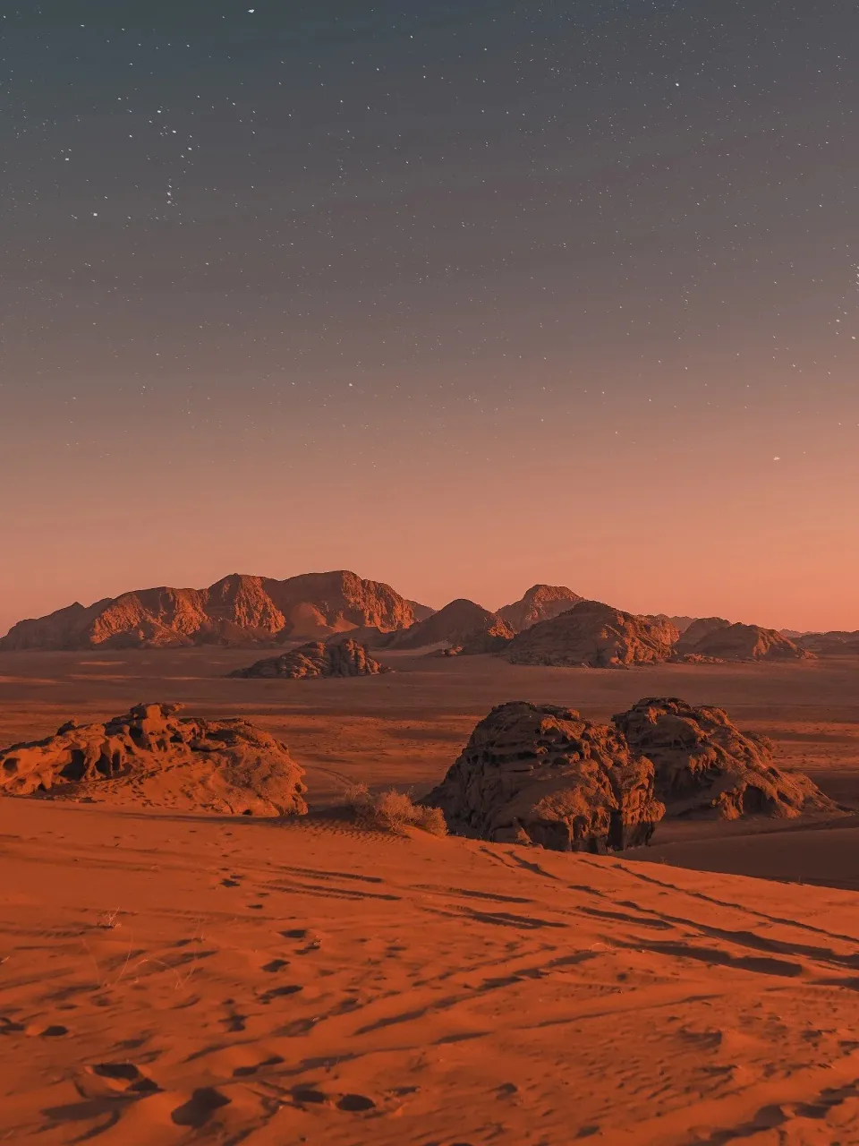 a desert landscape with rocks and a star filled sky