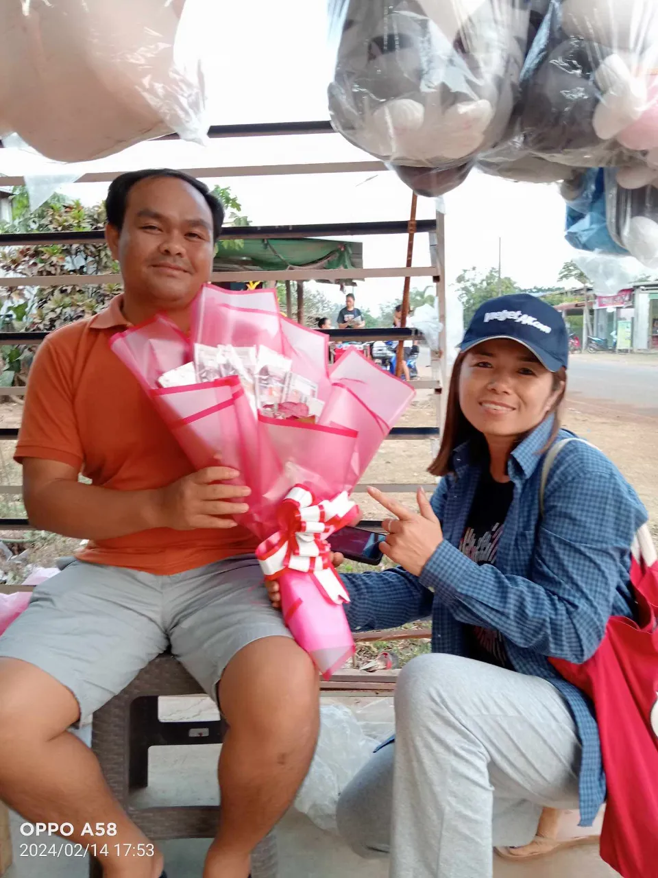 a man and woman sitting on a bench holding flowers