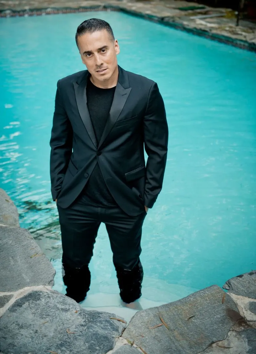 a man in a tuxedo standing in front of a pool