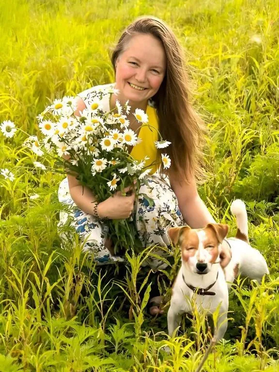 a woman kneeling in a field holding a bouquet of flowers