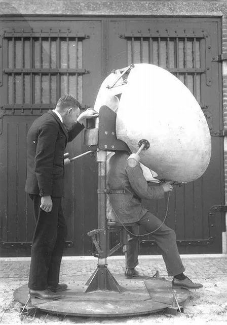 a black and white photo of two men working on a large object