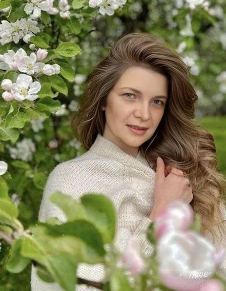 a woman with long hair standing in front of flowers, The woman is motionless, the wind moves the twigs and the woman's hair
