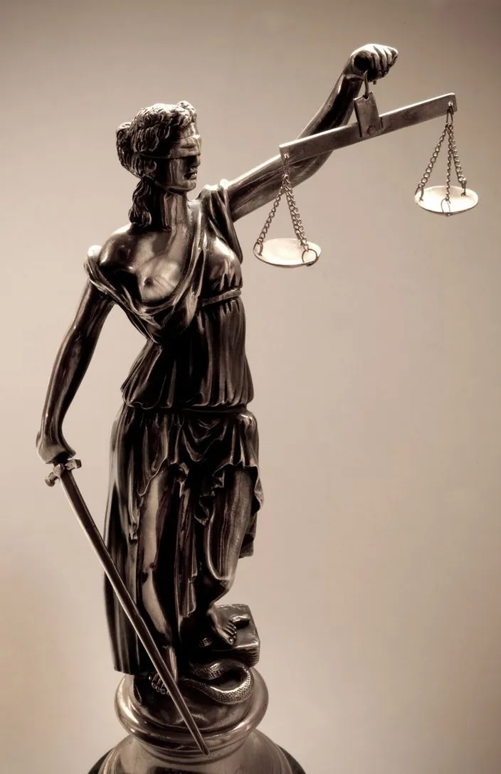 a statue of lady justice holding a sword and a scale cinematic courtroom scene