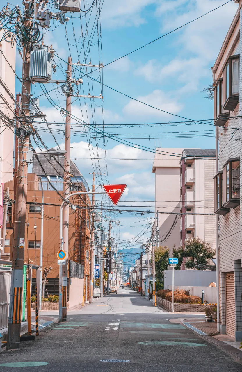 a street with power lines above it and a stop sign above it in Osaka Japan