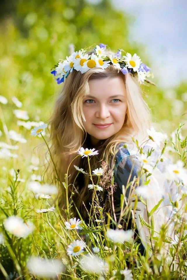 a girl with a wreath of daisies in a field of daisies The background is motionless, flowers are waving