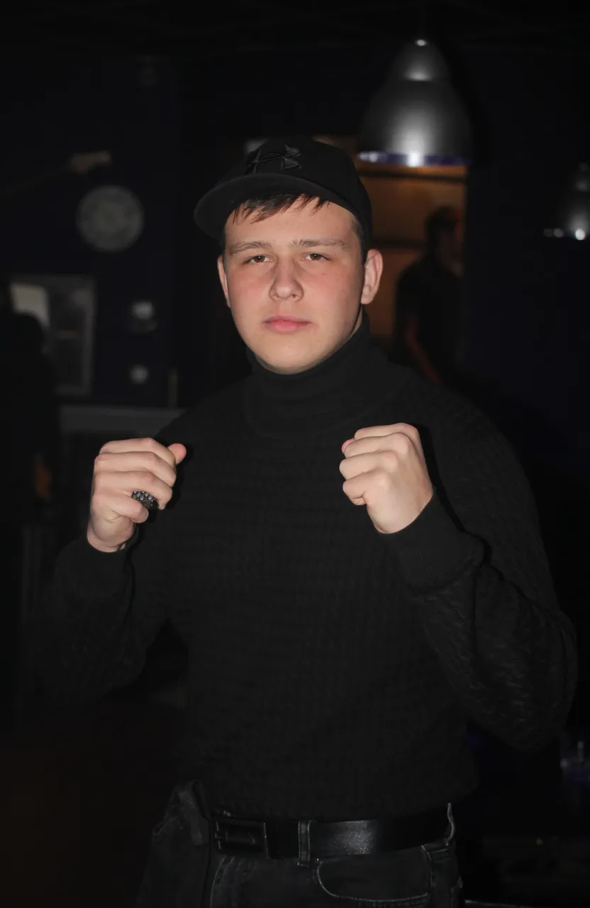 a young man wearing a black sweater and a black hat