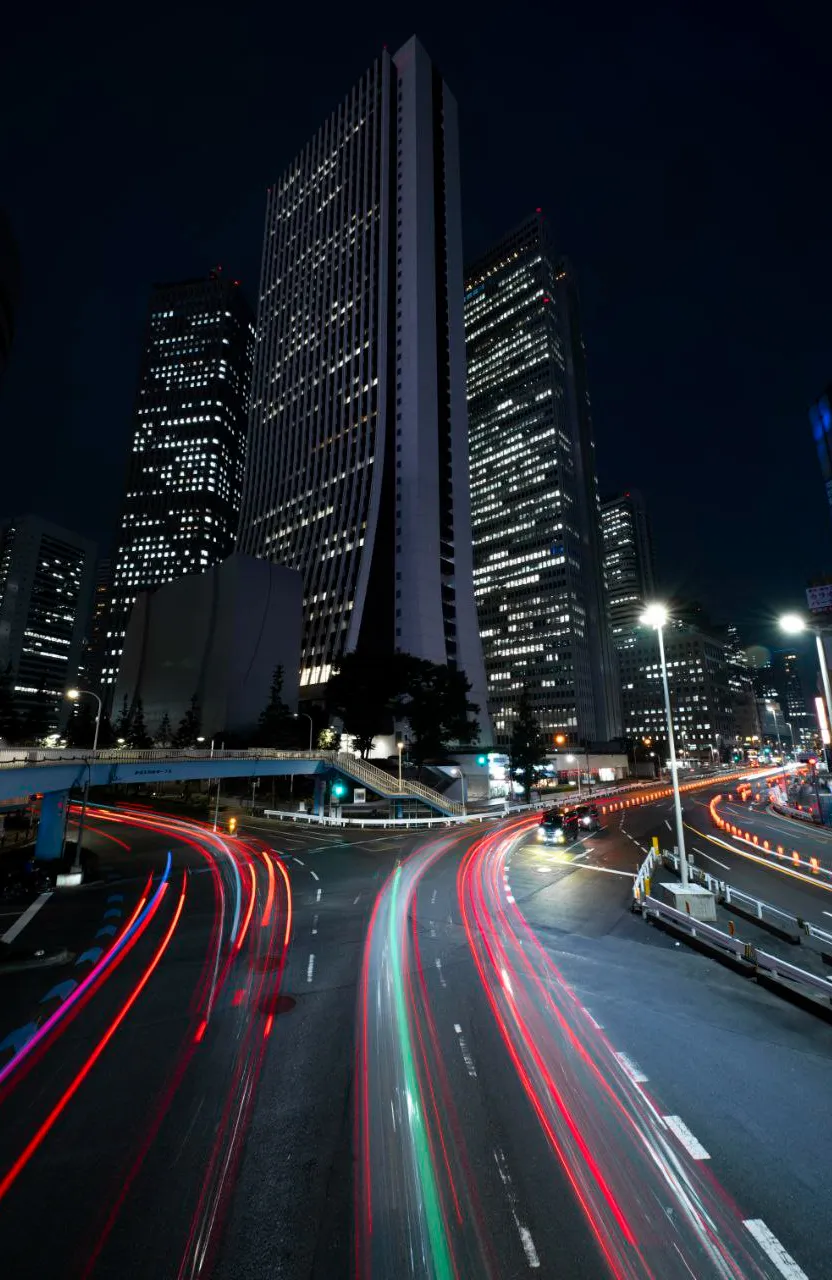 a city street at night with a very tall building in the background