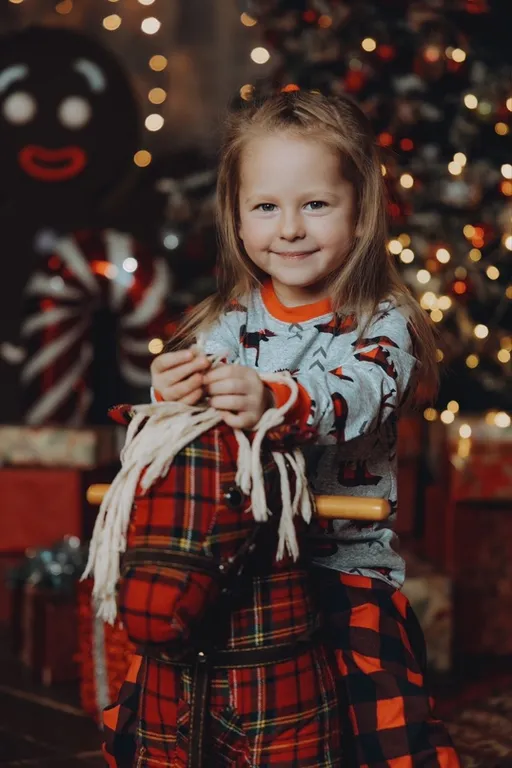 a little girl that is standing in front of a christmas tree